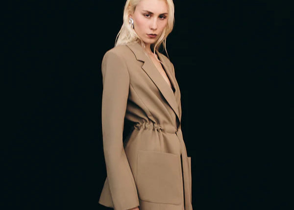 Woman wearing a beige suit against a black background